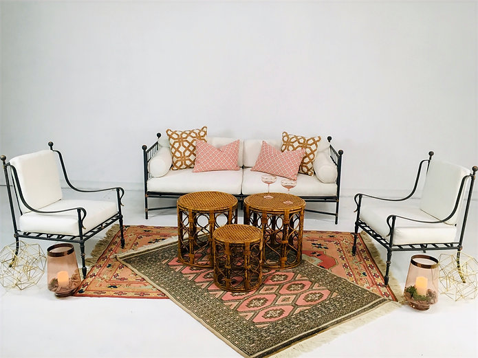 Outdoor-style metal-framed sofa and armchairs with white cushions and patterned pillows on a patterned rug