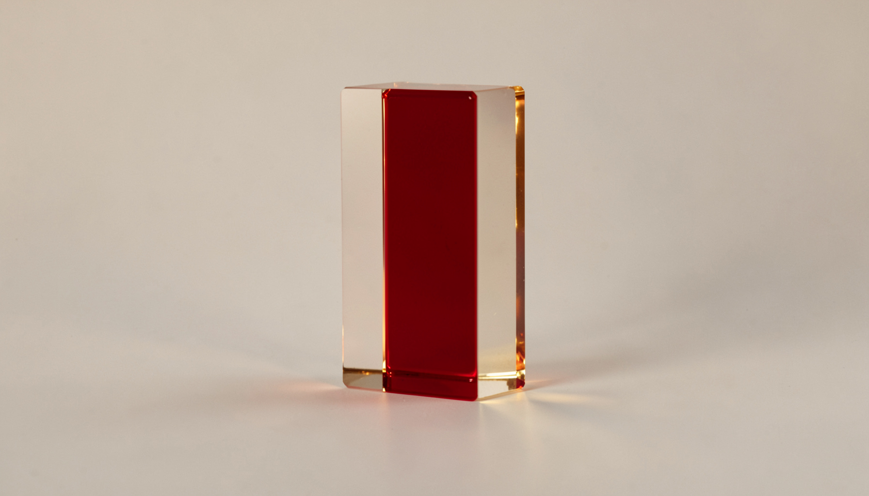 A transparent Lucite bar with polished edges, reflecting soft golden light, set against a neutral backdrop.